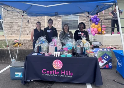 Outdoor community event with staff, table display, and balloon decorations.