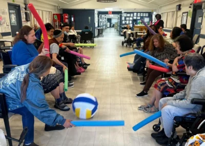 Indoor group activity with residents seated in a circle and staff leading exercises on a gym floor