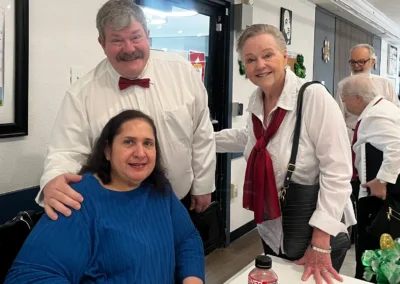 Staff members in formal attire posing with a resident during a themed celebration event.