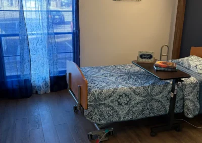 Interior bedroom with patterned bedding, curtains, and hardwood flooring.